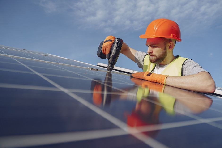 Worker carefully installing a solar panel on a residential roof